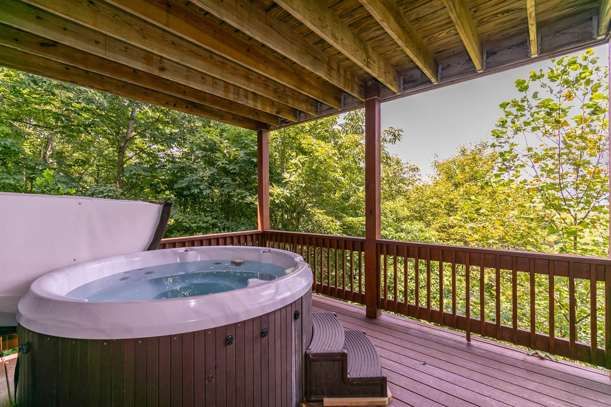This image showcases an inviting exterior hot tub set on a wooden deck, surrounded by lush greenery. The scene exudes tranquility and luxury, with the hot tub positioned to offer immersive nature experiences and sunset views. The outdoor setting suggests relaxation after a day spent exploring the area.