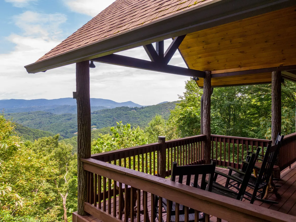 A peaceful wooden deck with inviting rocking chairs set against a breathtaking mountain landscape. The scene captures the tranquility of mornings spent with coffee or evenings under the stars, all from the comfort of the wraparound deck.
